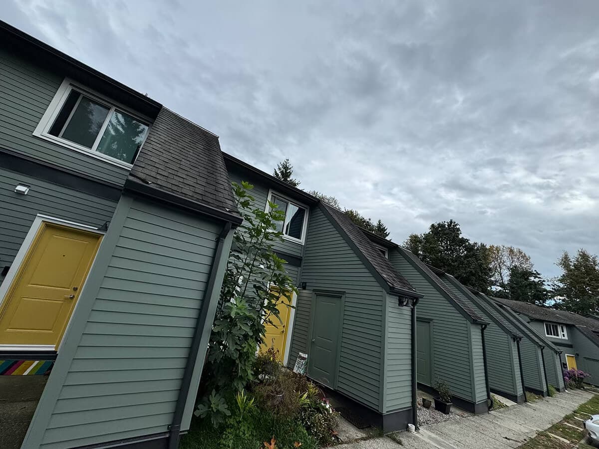 The La Coeur Housing Co–op, a row of modern green townhouses with yellow doors under a cloudy sky.