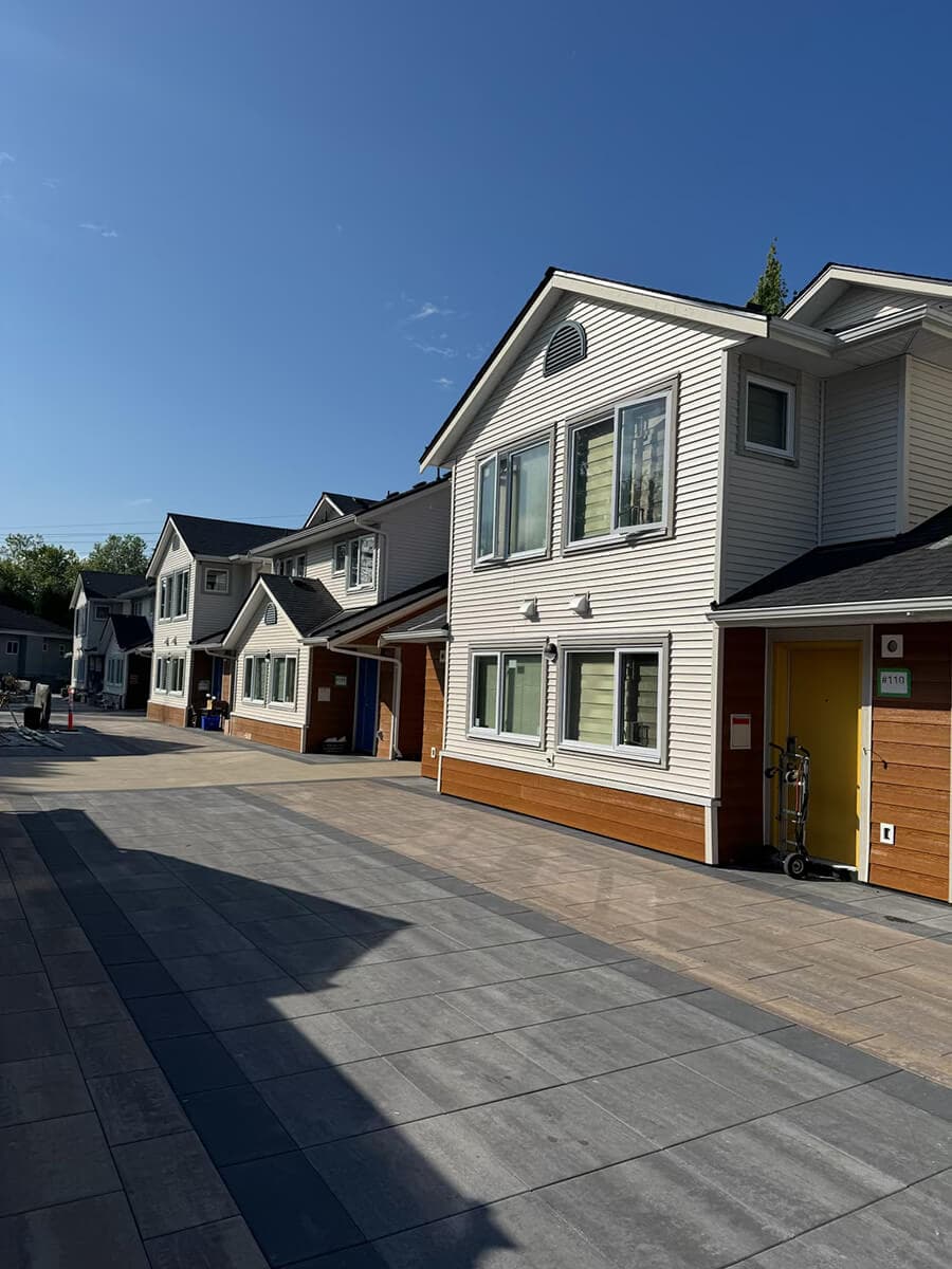 Row of modern townhomes with new two-tone siding, featuring white upper panels and wood-style lower panels.