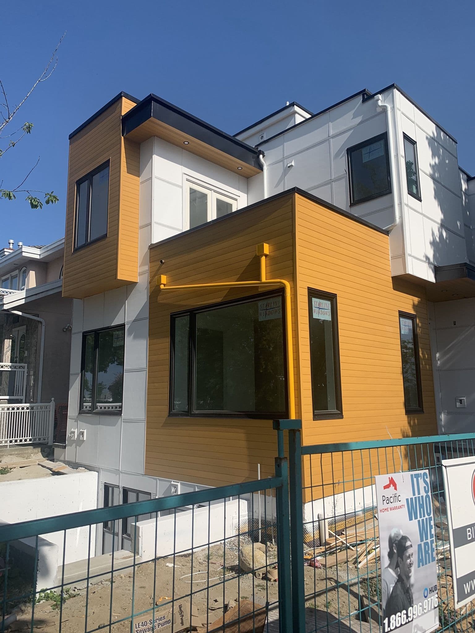 Modern, square, house with yellow and white siding.