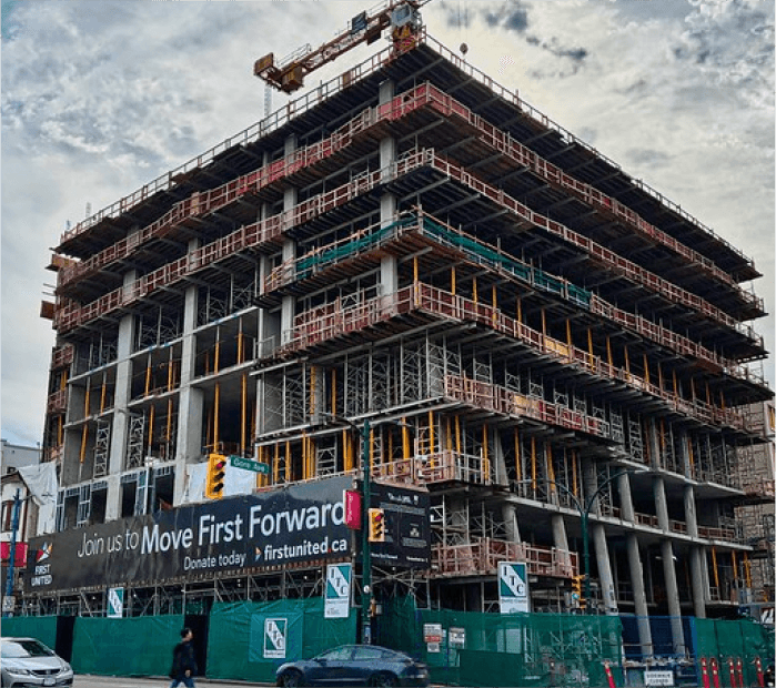 High-rise concrete building under construction with scaffolding and crane on site