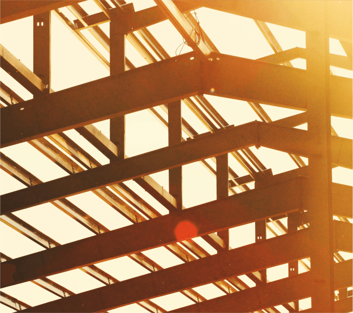 Steel framework of a building under construction with sunlight shining through beams